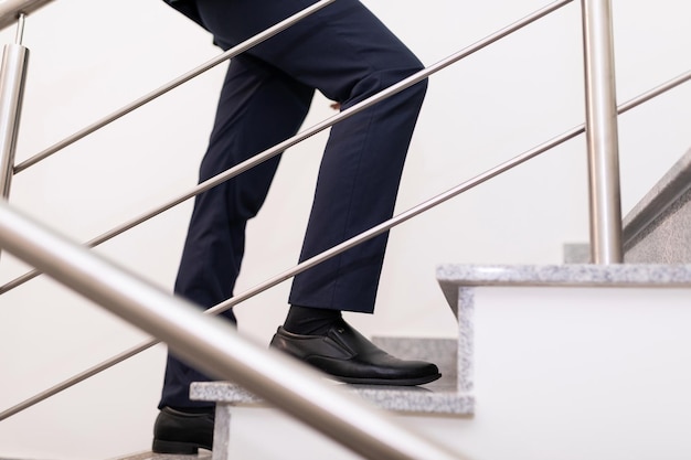 Zbliżenie na nogi biznesmena wspinającego się po schodach koncepcja udanego biznesu i