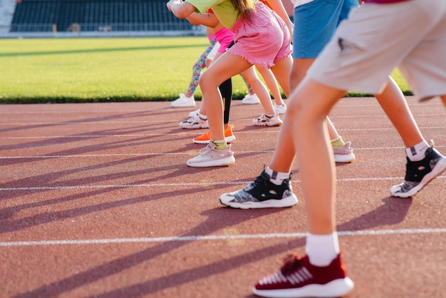 Zbliżenie na nogi chłopców i dziewcząt na starcie przed bieganiem i uprawianiem sportu na stadionie podczas zachodu słońca Zdrowy styl życia