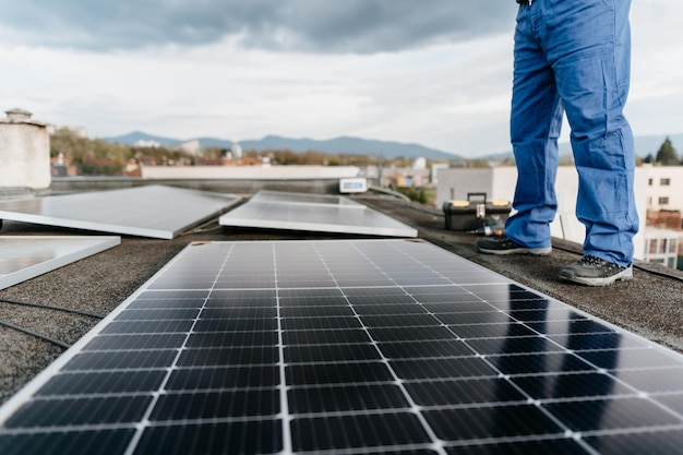 Zbliżenie na nogi mężczyzny stojącego przy panelach słonecznych na dachu domu Alternatywne źródła energii Zdjęcie na okładce