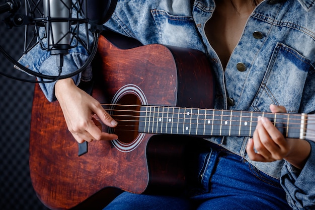 Zbliżenie na palce kobiety trzymające mediatora z gitarą nagrywającą piosenkę w studiu nagrań