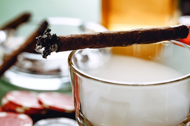Zbliżenie na palenie cygar i szkła whisky na stole
