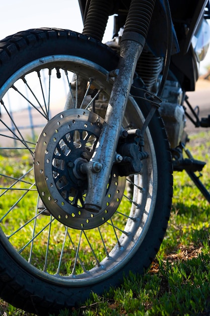 Zbliżenie na przednie koło motocykla zaparkowanego na trawie