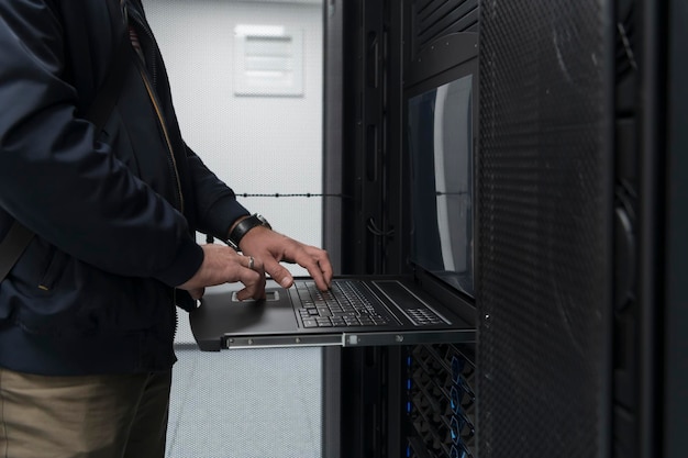 Zbliżenie na ręce inżyniera centrum danych Korzystanie z klawiatury na superkomputerze. Specjalista w zakresie serwerowni z męskim administratorem systemu współpracującym z siecią ochrony danych w celu zapewnienia cyberbezpieczeństwa.