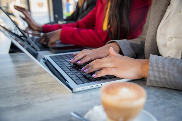 Zbliżenie na ręce kobiet pracujących przy użyciu laptopów i tabletów w pracownicach biurowych