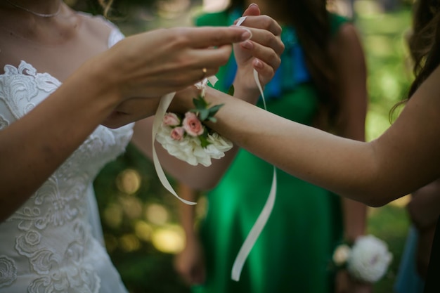 Zbliżenie na ręce panny młodej wiązanie opaski ślubnej na ręce druhny.