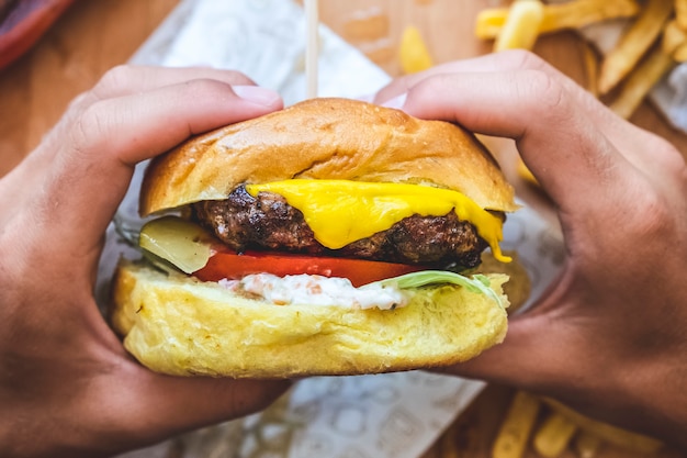 Zdjęcie zbliżenie na ręce, trzymając smaczny burger wołowy