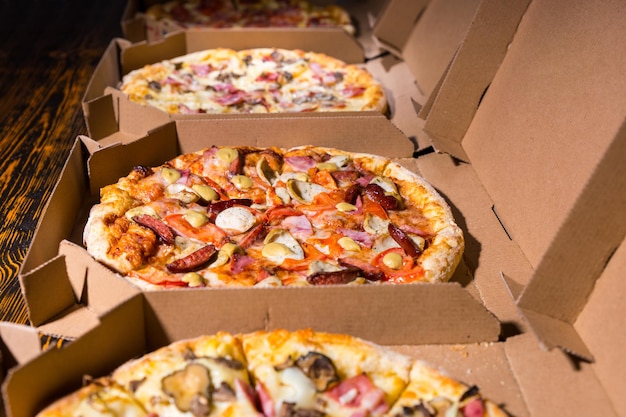 Zbliżenie Na Smaczne Pizze Z Różnymi Dodatkami I Serem W Kartonowych Pudełkach Z Otwartą Pokrywą Na Drewnianym Stole