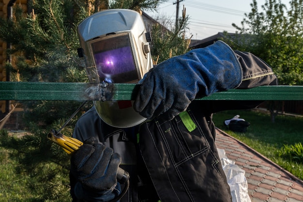 Zbliżenie na spawacza spawającego ogrodzenie na placu budowy we wsi