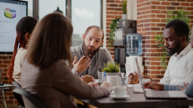 Zbliżenie na spotkanie pracowników ze współpracownikami do planowania projektu w biurze. Mężczyzna rozmawiający z kolegami z pracy w celu opracowania strategii marketingowej, burzy mózgów i używania dokumentów ze statystykami.