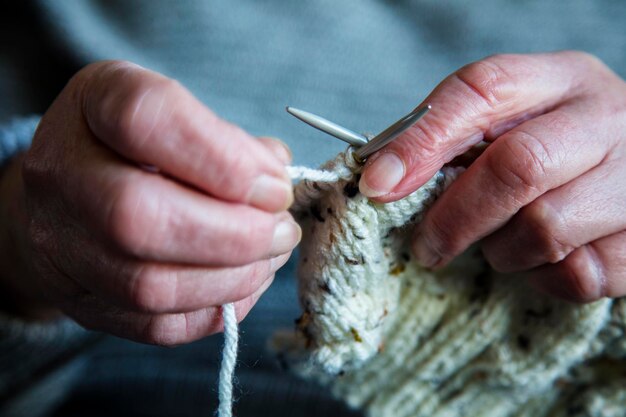 Zbliżenie na starsze damskie ręce dziergające sweter