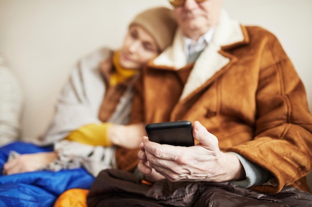 Zbliżenie na starszego mężczyznę ukrywającego się w schronie i trzymającego telefon bez miejsca na kopiowanie połączenia internetowego