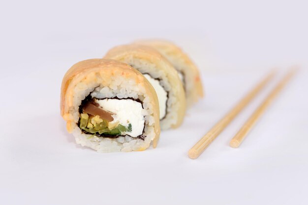 Zbliżenie na sushi i pałeczki do sushi na białym tleTrzy kawałki pysznego sushi