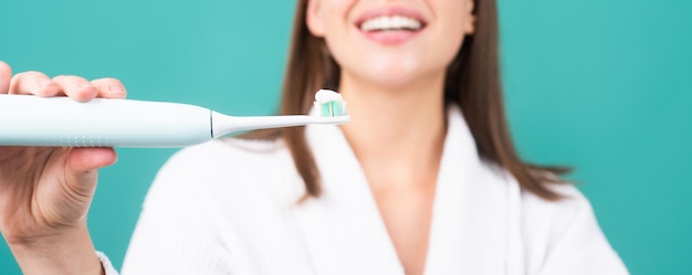Zbliżenie na szczęśliwą młodą kobietę szczotkowanie zębów szczoteczką do zębów z pastą do zębów elektryczna szczoteczka do zębów transparent co