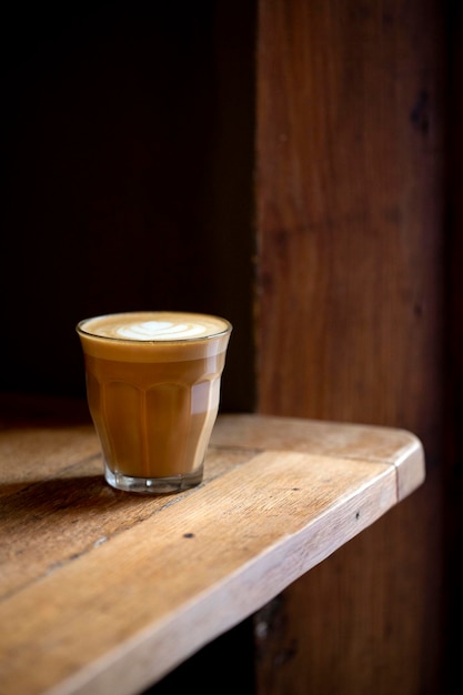 Zbliżenie na szklankę cafe latte na rustykalnym drewnianym stole w kawiarni