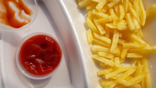 Zbliżenie Na Złoto-pomarańczowo-żółte Frytki Z Keczupem W Piankowym Pojemniku. Fast Food Na Wynos. Niechciana świeża żywność.