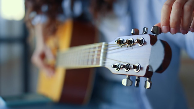 Zdjęcie zbliżenie nie do poznania dziewczyna ręce strojenie gitary młoda kobieta sprawdza kołki gitary akustycznej gitarzysta strojenie dźwięku instrumentu muzycznego pani trzyma instrument smyczkowy w rękach