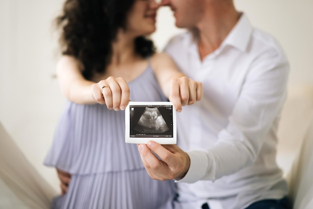 Zbliżenie nierozpoznawalnej kobiety w ciąży z obrazem USG w ręku