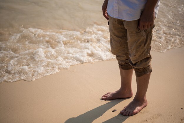 zbliżenie nogi człowieka stoi na plaży z fali z morza rano na lato