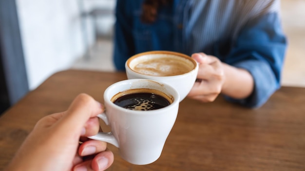 Zbliżenie obraz kobiety i mężczyzny brzęk filiżanek kawy razem w kawiarni