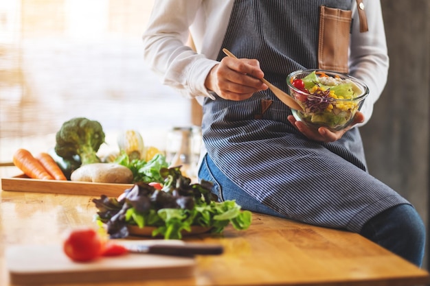 Zbliżenie obraz kobiety szefa kuchni gotującej i trzymającej miskę sałatki ze świeżych warzyw mieszanych do jedzenia w kuchni