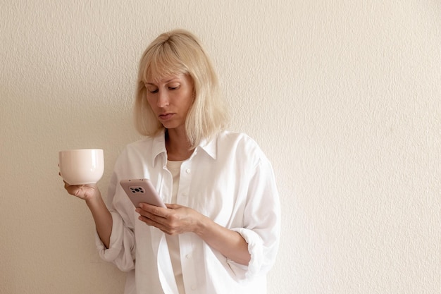 Zbliżenie obraz ładna kobieta siedzi w przytulnym wnętrzu domu i przy użyciu nowoczesnego urządzenia smartphone kobiece ręce pisania wiadomości tekstowej za pośrednictwem koncepcji sieci społecznościowych telefonu komórkowego