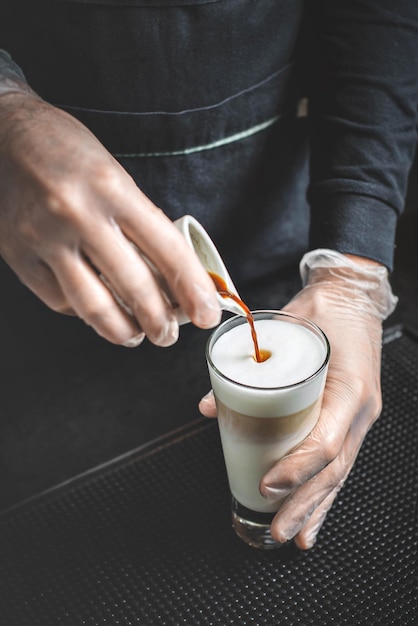 Zbliżenie obraz męskich rąk wlewając mleko i przygotowując świeże cappuccino, artysta kawy i koncepcja przygotowania, poranna kawa