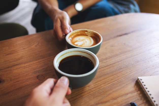 Zbliżenie obraz mężczyzny i kobiety stukających się kubkami kawy w kawiarni