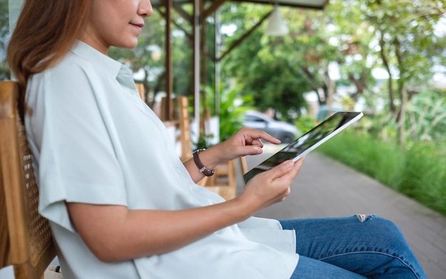 Zbliżenie obraz młodej azjatyckiej kobiety trzymającej i dotykającej na ekranie cyfrowego tabletu