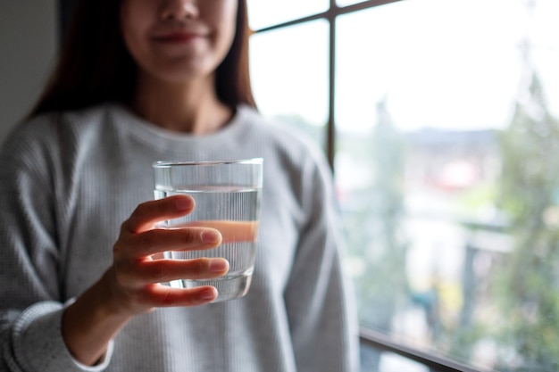 Zbliżenie obraz pięknej młodej azjatyckiej kobiety trzymającej szklankę wody do picia