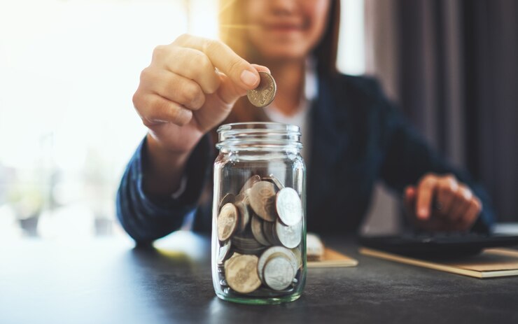 Zdjęcie zbliżenie obrazu bizneswoman zbierającej i wkładającej monety do szklanego słoika