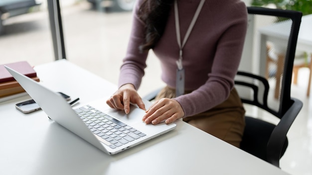 Zbliżenie obrazu businesswoman za pomocą swojego laptopa przy biurku w biurze