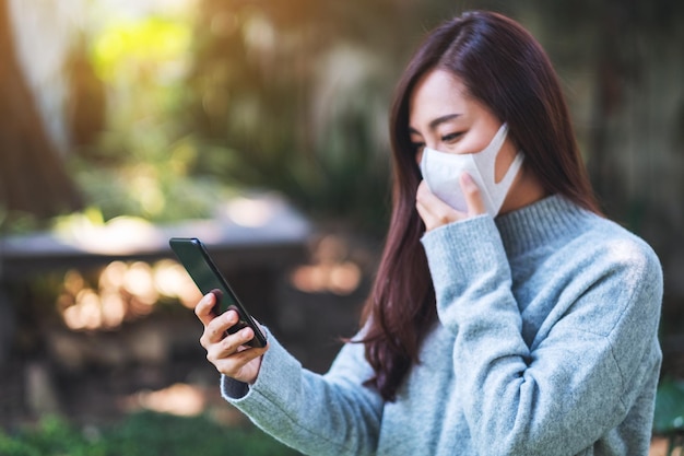 Zbliżenie obrazu chorej kobiety noszącej maskę ochronną, używającego telefonu komórkowego do koncepcji opieki zdrowotnej i Covid-19