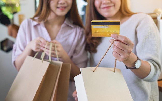 Zbliżenie obrazu dwóch młodych kobiet posiadających torby na zakupy i kartę kredytową do zakupu