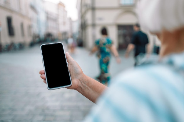 Zbliżenie obrazu kobiecych rąk za pomocą smartfona na ulicy handlowej w mieście lub koncepcji sieci społecznościowych