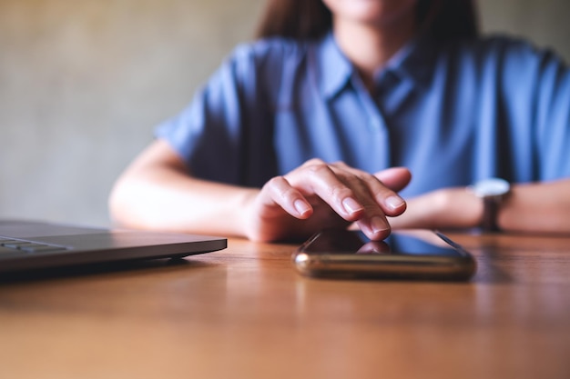 Zbliżenie obrazu kobiety korzystającej z telefonu komórkowego i laptopa