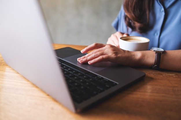 Zbliżenie obrazu kobiety pijącej kawę podczas pracy na laptopie