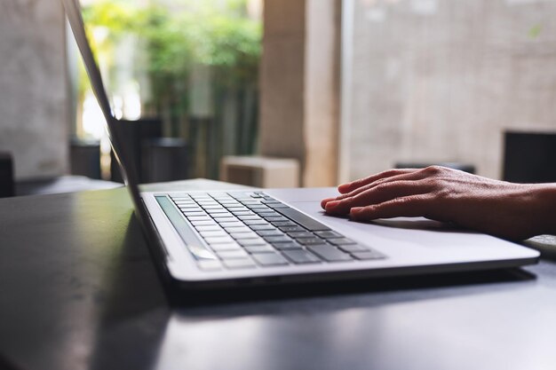 Zbliżenie obrazu kobiety pracującej i dotykającej na panelu dotykowym laptopa na stole