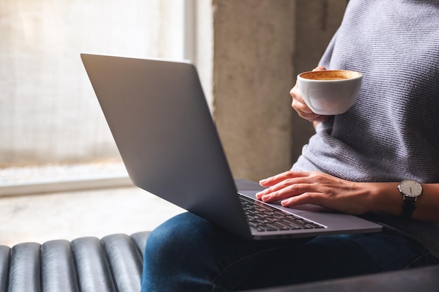 Zbliżenie obrazu kobiety pracującej i dotykającej touchpada laptopa podczas picia kawy