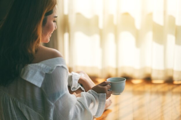 Zbliżenie Obrazu Kobiety Siedzącej Rano I Trzymającej Filiżankę Gorącej Kawy Na Podłodze