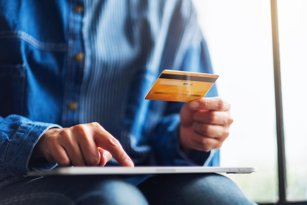 Zbliżenie obrazu kobiety trzymającej kartę kredytową podczas korzystania z komputera typu tablet