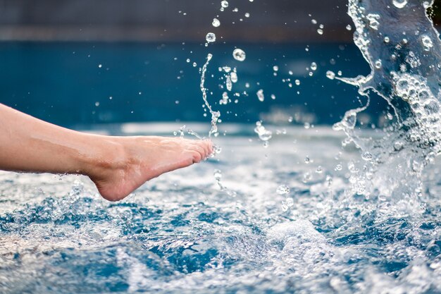 Zbliżenie obrazu nóg i bosych kopnięć i rozpryskiwania wody w basenie