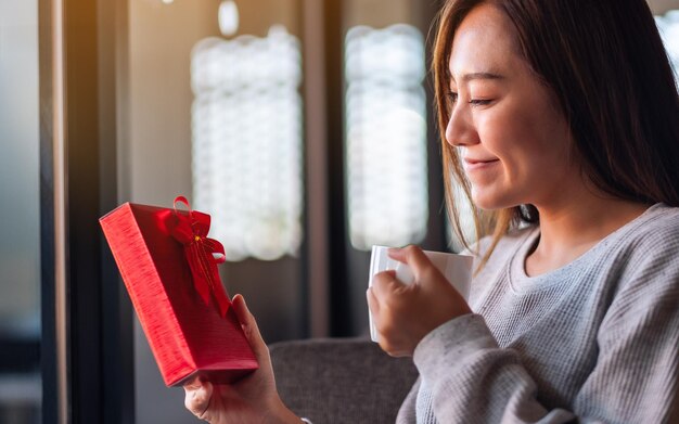 Zbliżenie obrazu pięknej młodej azjatyckiej kobiety trzymającej i otrzymującej czerwone pudełko na prezent