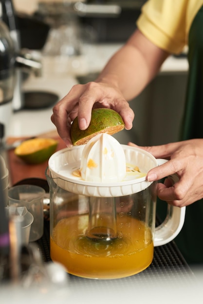 Zbliżenie obrazu pracownika kawiarni za pomocą sokowirówki podczas wyciskania pomarańczy