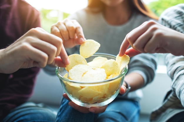 Zbliżenie obrazu przyjaciół dzielących się i jedzących chipsy ziemniaczane na imprezie domowej razem