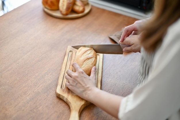 Zbliżenie obrazu uroczej pary krojącej chleb nożem razem przygotowującej jedzenie w kuchni