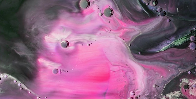 Zbliżenie obrazu wykonanego różową i fioletową farbą z czarnym tłem.