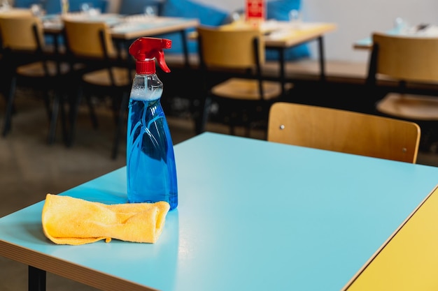 Zbliżenie odkażający detergent w sprayu i ściereczka do czyszczenia na stole w restauracji