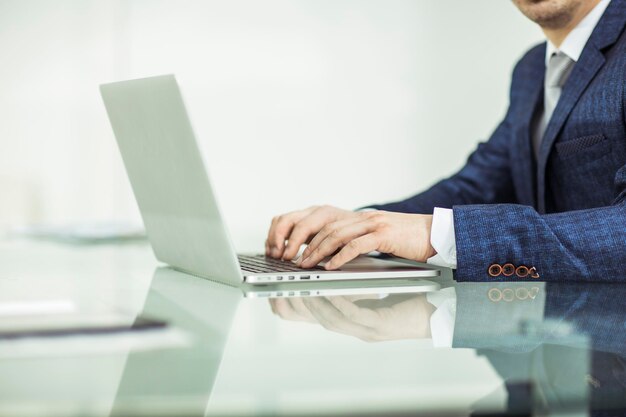 Zbliżenie - odnoszący sukcesy biznesmen pracujący na laptopie w miejscu pracy. Zdjęcie ma puste miejsce na tekst