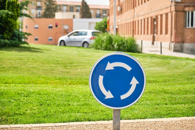 Zdjęcie zbliżenie okrągłego niebieskiego znaku drogowego przymusowego ruchu na rondzie z trawą