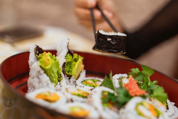 Zbliżenie osoby trzymającej sushi na stole